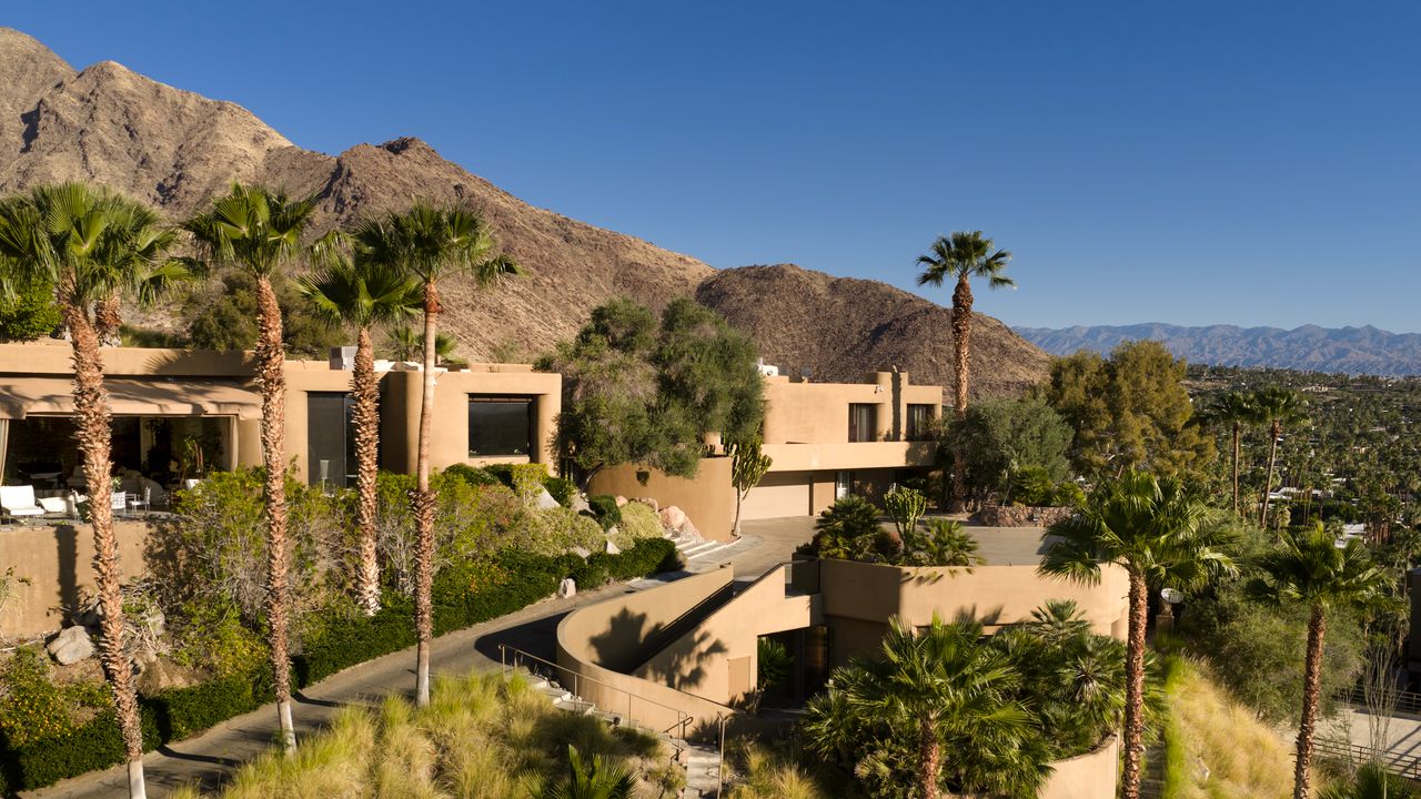 Guesthouse exterior framed by mountains and palms